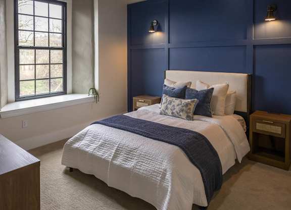 A bedroom with a bed, nightstand, and window at The Dean at Creekview Apartments, Newark, DE