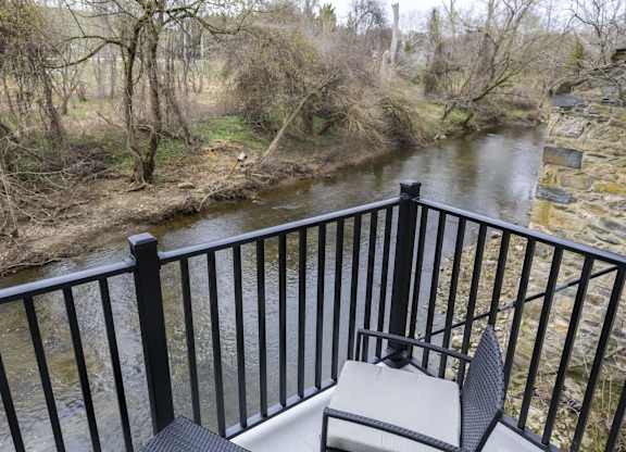 A balcony overlooks a river with a black railing at The Dean at Creekview Apartments, Newark, 19711