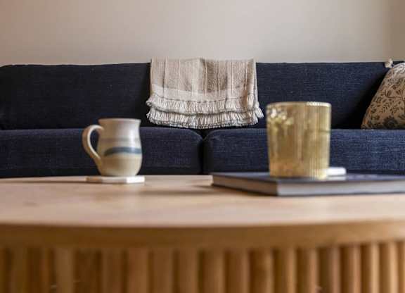 A blue couch with a white blanket and a cup on a table in front of it at The Dean at Creekview Apartments, Newark, DE, 19711