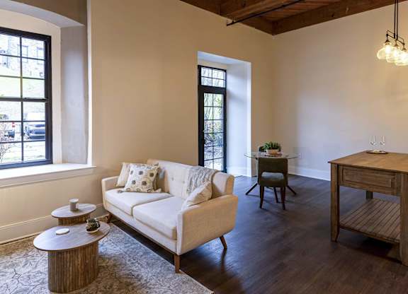 A living room with a white couch, wooden coffee table, and a wooden side table at The Dean at Creekview Apartments, Newark
