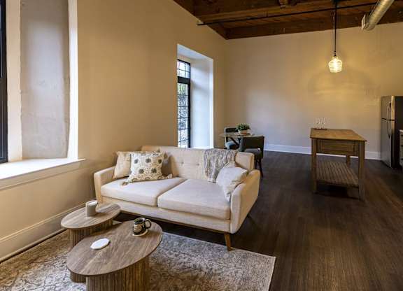 A living room with a white couch and a wooden coffee table at The Dean at Creekview Apartments, Newark, Delaware