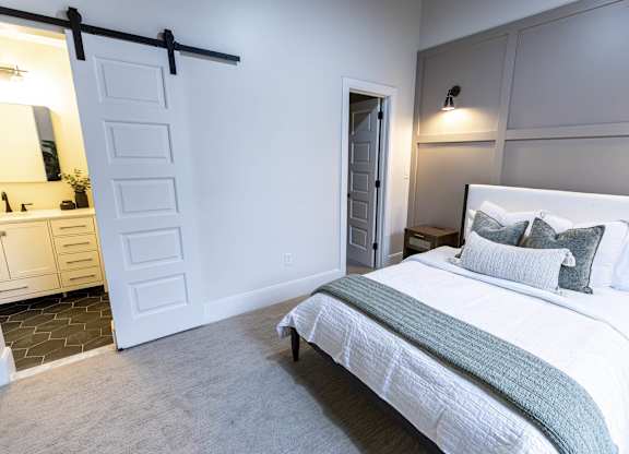 A bedroom with a large bed and a dresser at The Dean at Creekview Apartments, Newark, DE