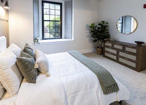 A bedroom with a large bed and a mirror on the wall at The Dean at Creekview Apartments, Newark, Delaware