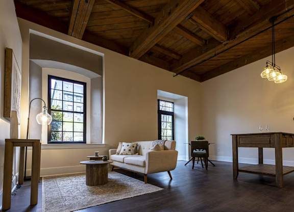 A living room with a couch, a chair, a table, and a rug at The Dean at Creekview Apartments, Newark, Delaware
