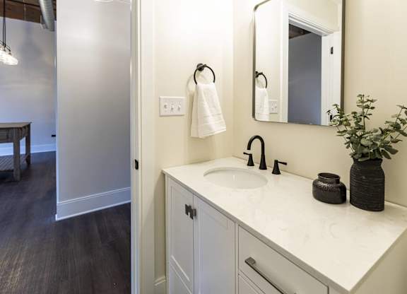 A white bathroom sink with a black vase and towel hanging on the wall at The Dean at Creekview Apartments, Delaware