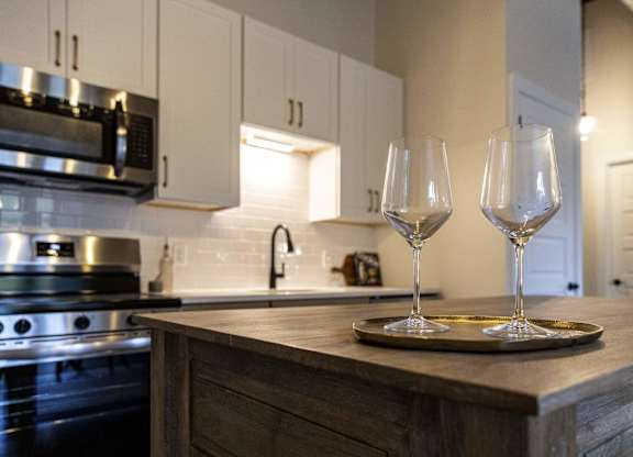 Two wine glasses are placed on a tray on a kitchen counter at The Dean at Creekview Apartments, Newark, 19711