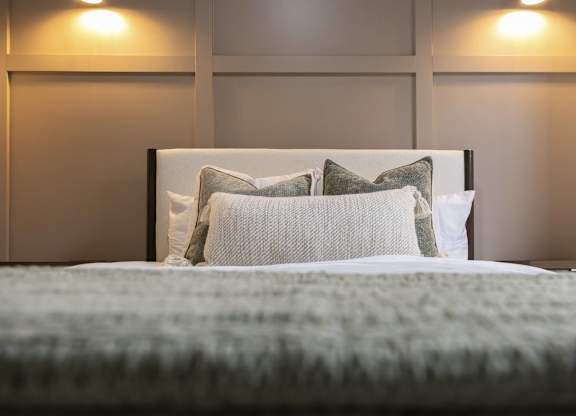 A bed with a white comforter and two pillows at The Dean at Creekview Apartments, Newark