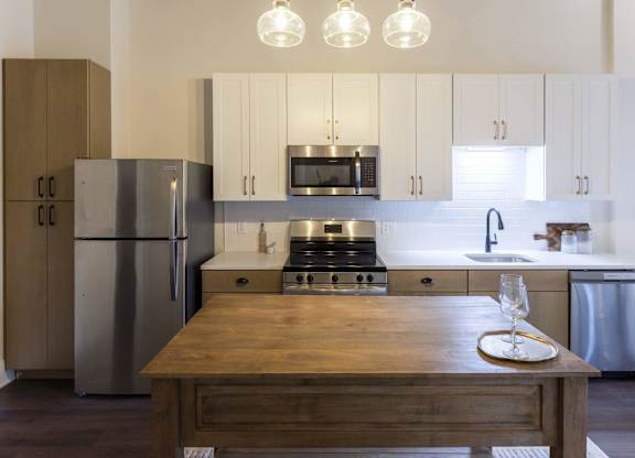 A modern kitchen with a wooden table in the center at The Dean at Creekview Apartments, Newark