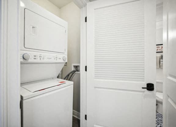 a laundry room with a washer and dryer and a white door at Park Kennedy, Washington