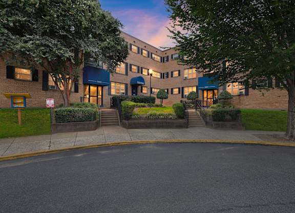 A building with a blue awning and a tree in front of it at Huntwood Courts Apartments, Washington DC