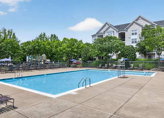 A large swimming pool surrounded by trees and apartment buildings.