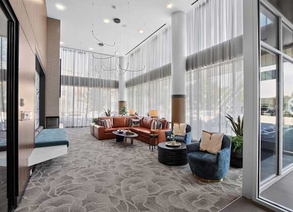 A modern living room with a grey carpet and a variety of seating options.