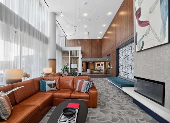 A modern living room with a brown leather couch and a fireplace.