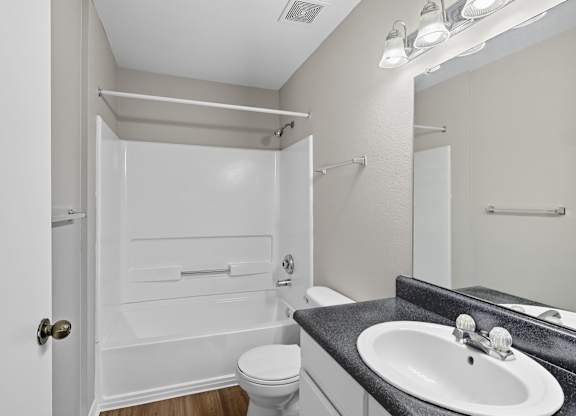 A white bathroom with a toilet, sink, and shower. at Greens at Stonecreek, Lithonia, GA