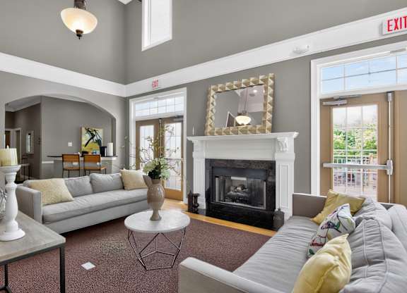 A living room with a grey couch, a fireplace, and a mirror on the wall.