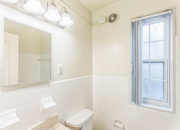 A white bathroom with a toilet, sink, and mirror.