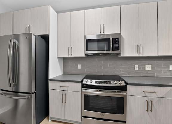 A kitchen with a refrigerator, oven, and microwave.
