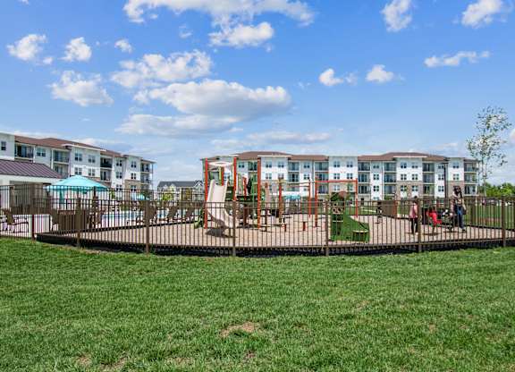 A playground with a swing set and a building in the background.