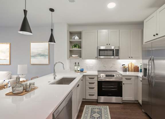 A modern kitchen with white cabinets and stainless steel appliances. at The Sully, Virginia, 20151