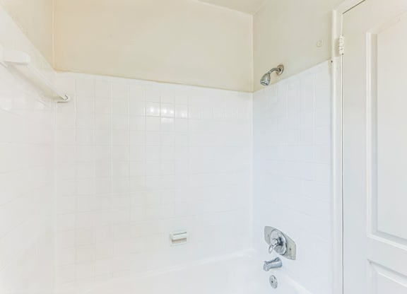 A white bathroom with a shower and a door.