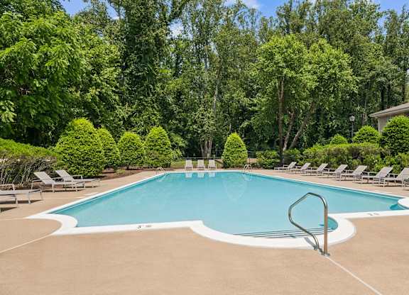 A large swimming pool surrounded by trees and lounge chairs at The Overlook at Quantico Apartments, Triangle, VA, 22172