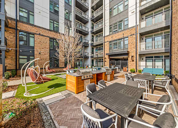A patio with a table and chairs is surrounded by buildings at Hawkins Press Apartments, Charlotte, NC