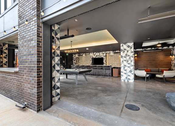 A modern outdoor seating area with a brick wall and patterned columns at Hawkins Press Apartments, Charlotte, North Carolina