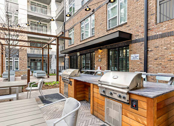 A wooden BBQ grill is in the middle of a patio at Hawkins Press Apartments, Charlotte, NC