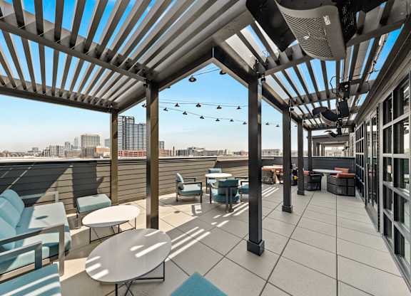 A rooftop patio with tables and chairs at Hawkins Press Apartments, Charlotte, NC