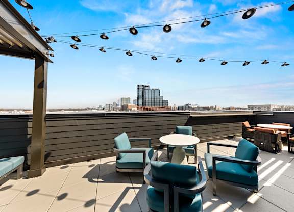 A rooftop patio with blue chairs and a table at Hawkins Press Apartments, Charlotte, NC