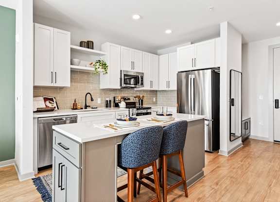 A kitchen with a white countertop and a stainless steel refrigerator.