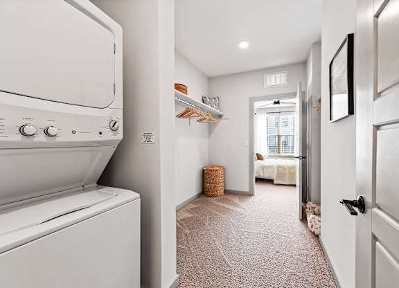 A white washing machine is in a narrow hallway.