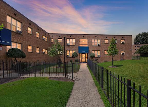 A building with a black fence and a walkway leading to the entrance at Huntwood Courts Apartments, Washington DC