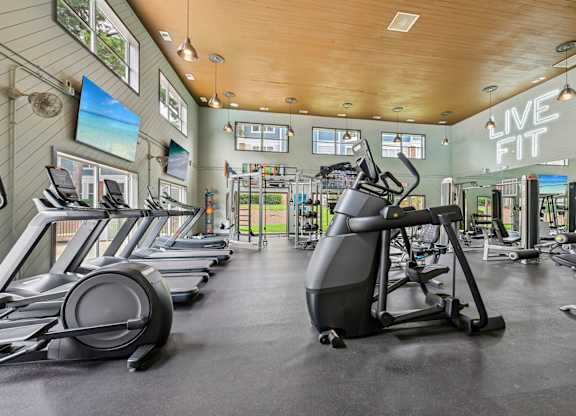 A gym with treadmills, elliptical machines, and other exercise equipment.