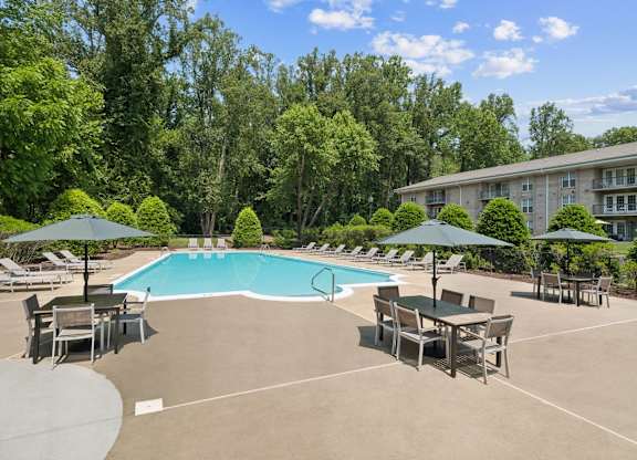 A large outdoor swimming pool surrounded by trees and lounge chairs at The Overlook at Quantico Apartments, Triangle, VA, 22172