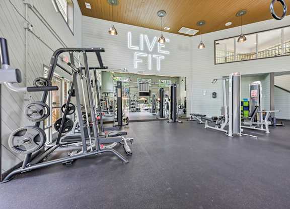 A gym with a variety of equipment and a sign that says "LIVE FIT".