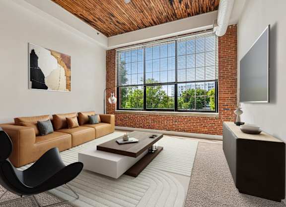 A living room with a brown leather couch, a black chair, a wooden coffee table, and a flat screen TV mounted on the wall.