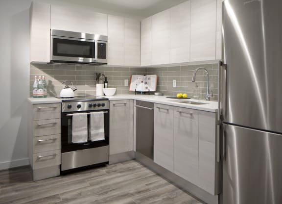 a small kitchen with stainless steel appliances and white cabinets at 1305 Dock Street, Maryland