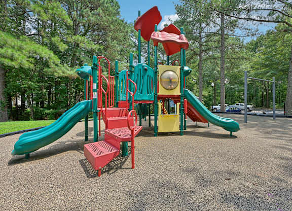 A playground with a green slide and red and yellow play structures.