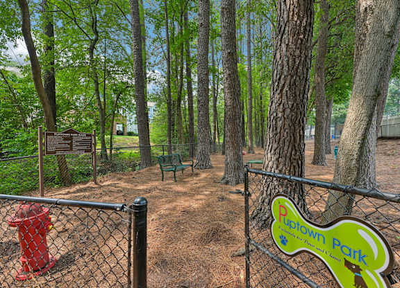 A sign for Rupown Park is on a fence in front of a tree.