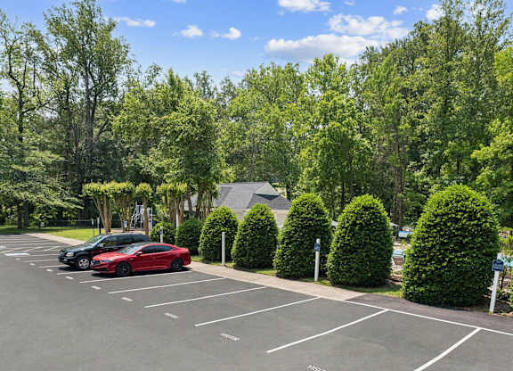 A parking lot with a red car and a black car parked in it at The Overlook at Quantico Apartments, Triangle, VA, 22172