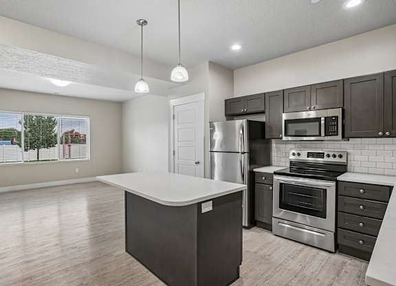 A kitchen with a white island and stainless steel appliances.