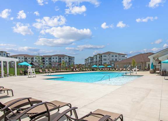 A large swimming pool surrounded by lounge chairs and umbrellas.