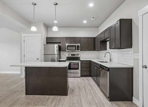 A modern kitchen with dark brown cabinets and stainless steel appliances.