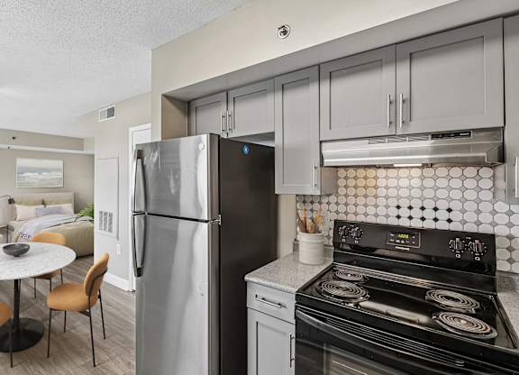 A modern kitchen with a refrigerator, stove, and dining table.