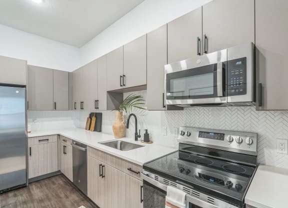 an apartment kitchen with stainless steel appliances and white cabinets  at La Unión, Tampa, FL
