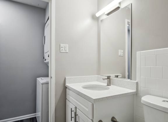 A white bathroom with a sink, mirror, and toilet at Shenandoah Station Apartments, Triangle