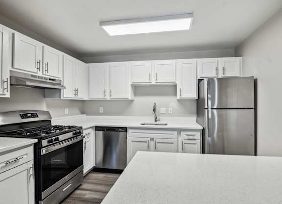 A kitchen with white cabinets and a stainless steel refrigerator at Shenandoah Station Apartments, Triangle, VA
