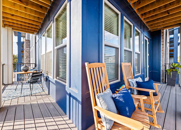 A balcony with wooden chairs and a table.