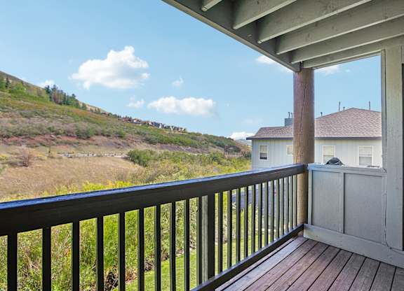 A balcony with a black railing overlooks a grassy hillside.